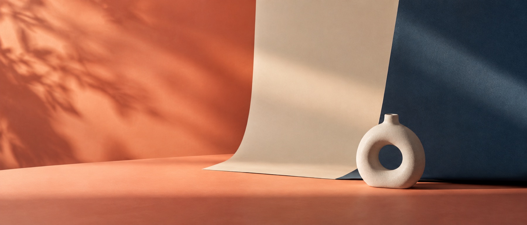 Layered paper backdrops and a sculptural object lit with a soft colour gradient.